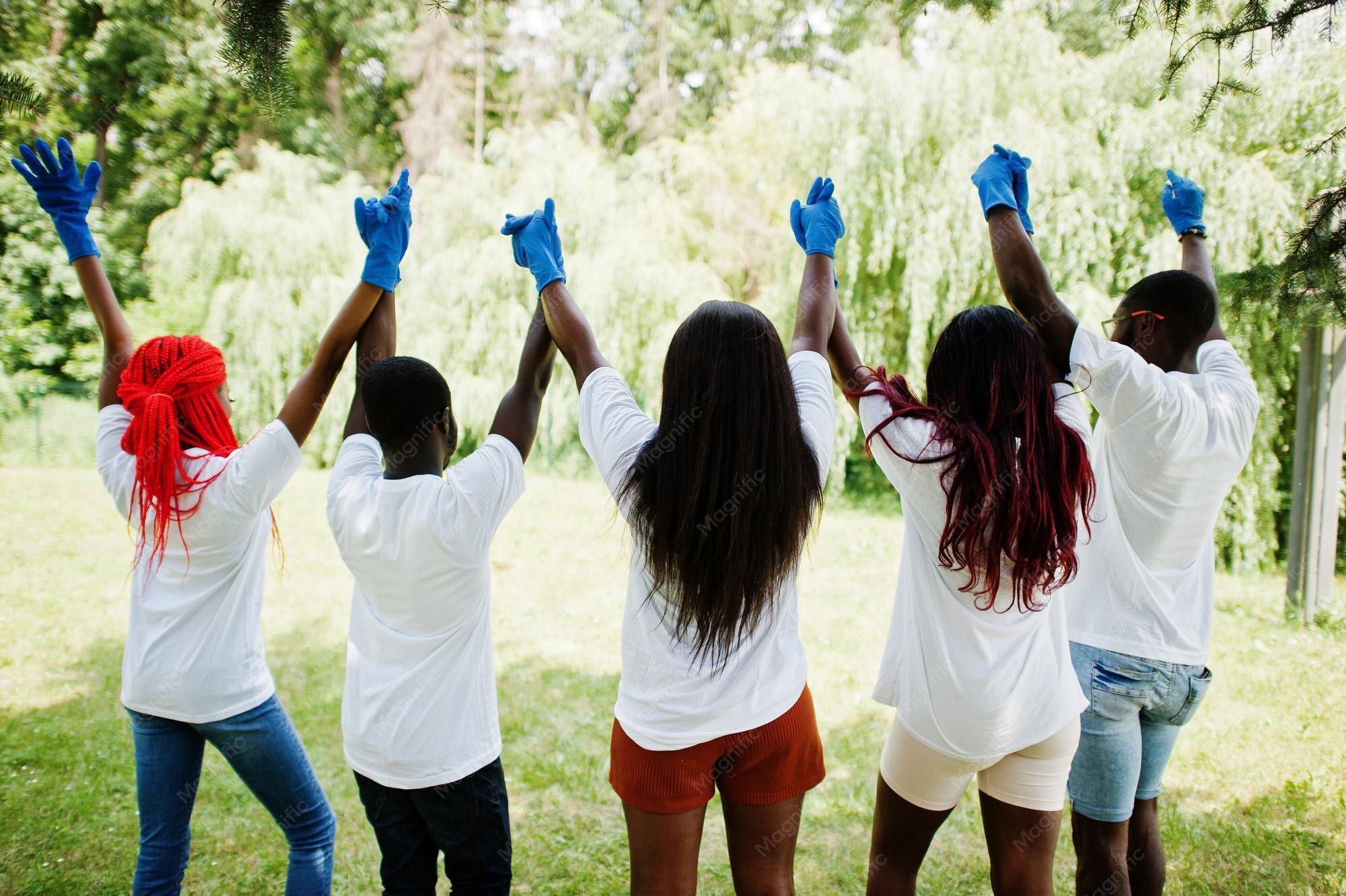 A group of volunteers holding hands and raising them together outdoors